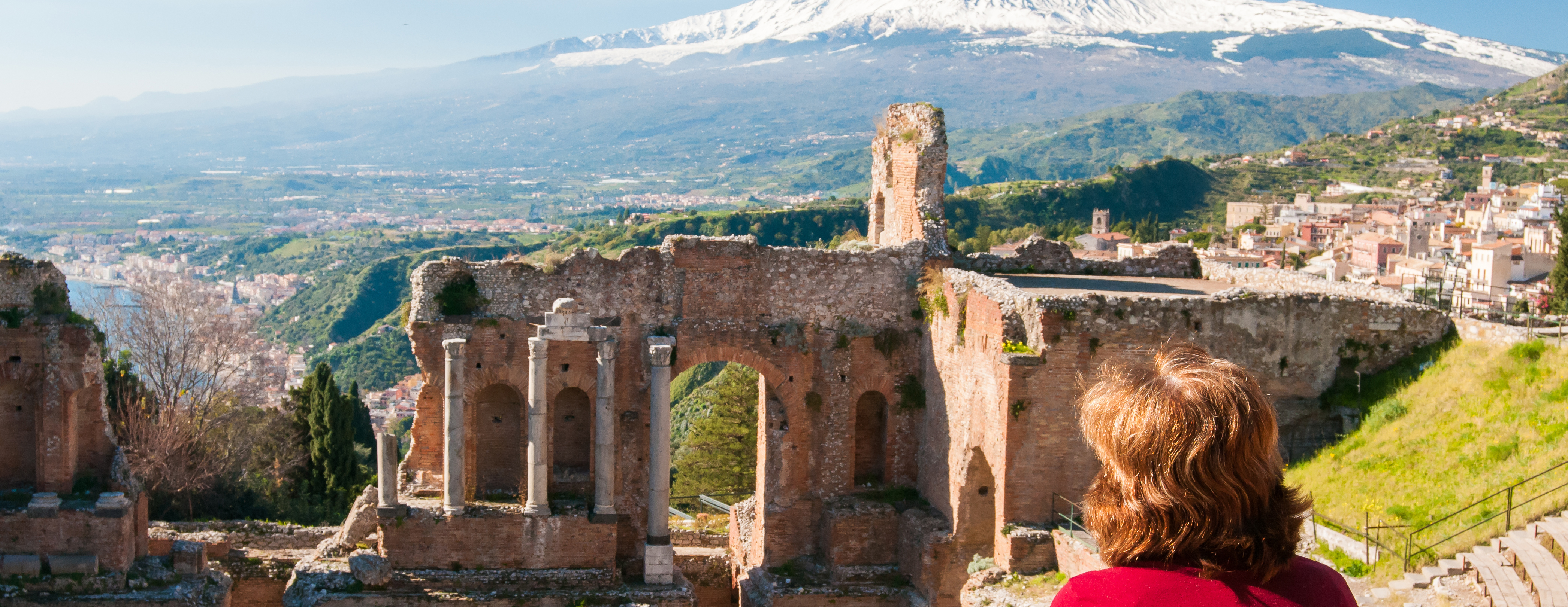 Turist i Taormina på Sicilien som blickar ut över amfiteatern och vulkanen Etna.